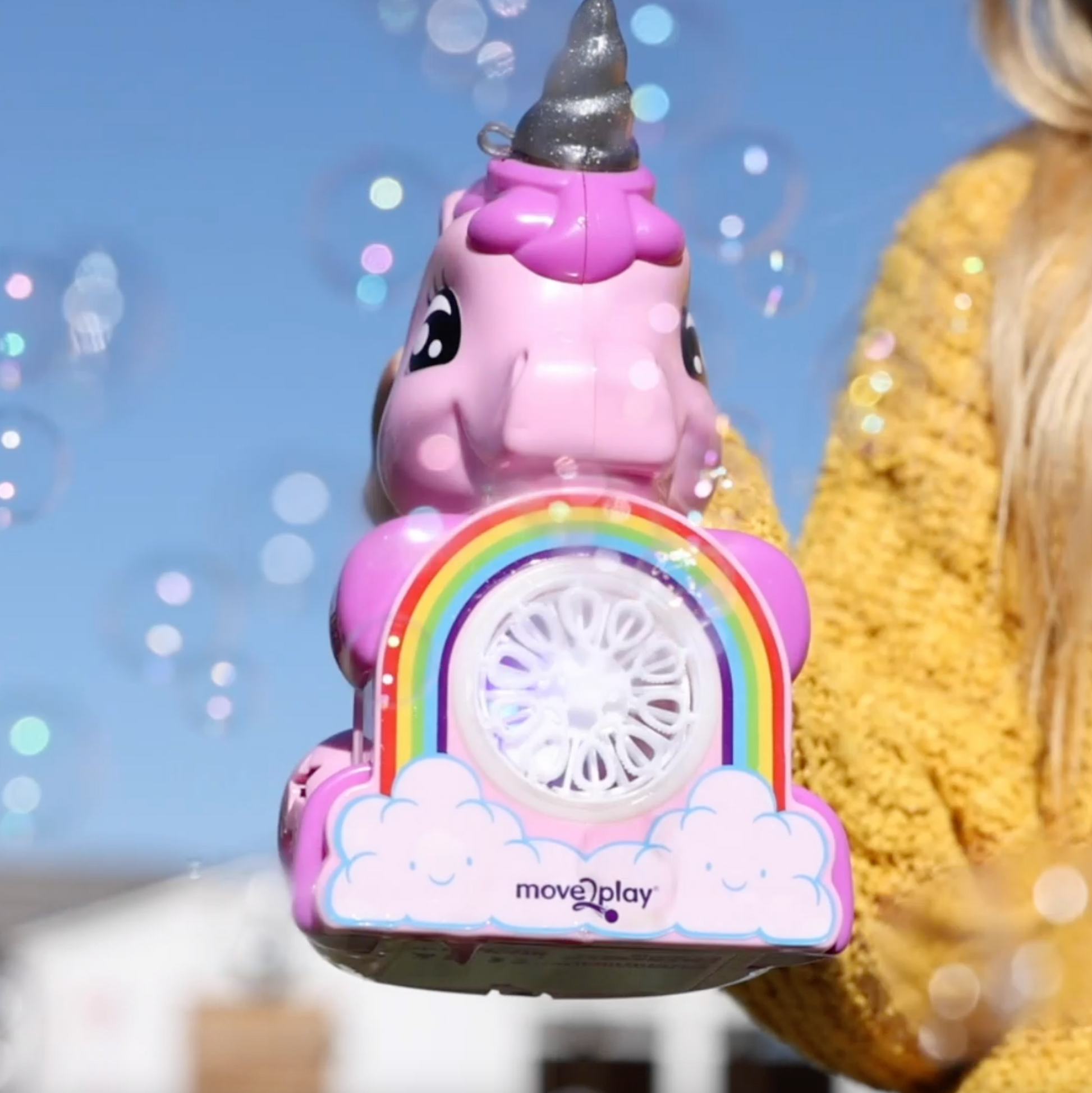 Child holding unicorn bubble blower toy with batteries and bubble solution included. Handheld design with durable, water-resistant features and easy-grip handle. Produces thousands of bubbles per minute for fun-filled occasions like birthdays and playdates.