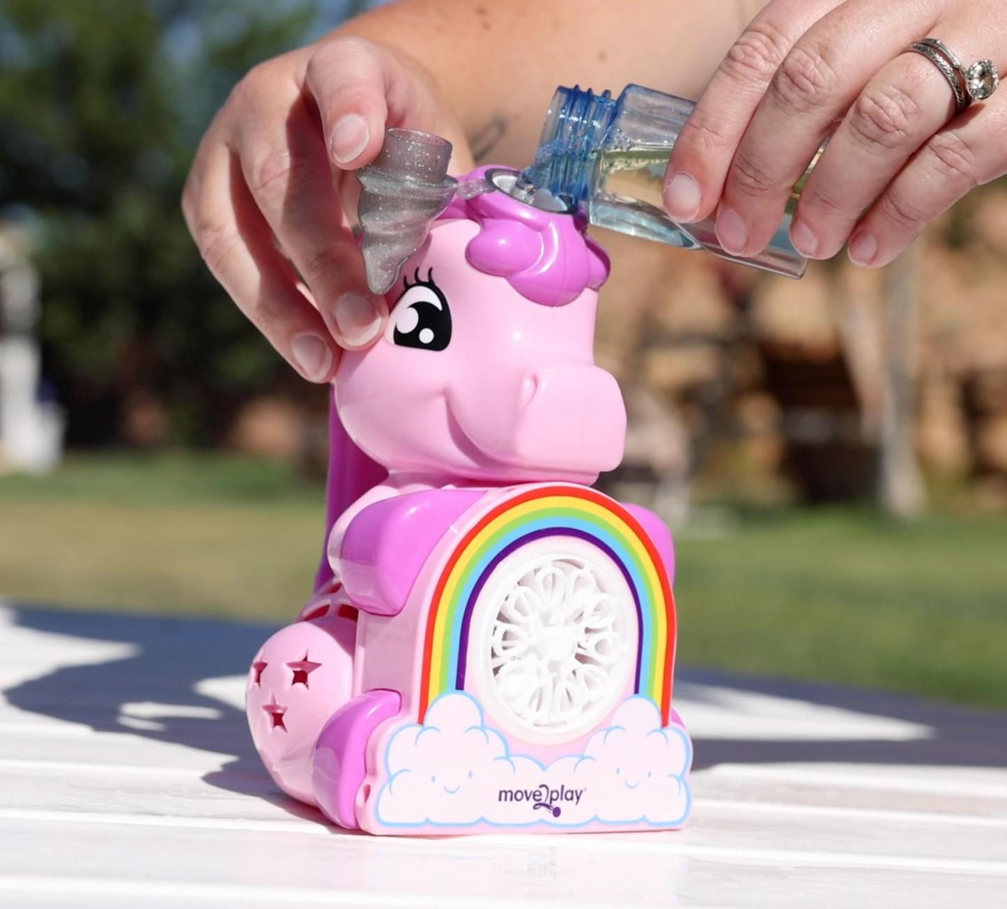 Child holding unicorn bubble blower toy with batteries and bubble solution included. Handheld design with durable, water-resistant features and easy-grip handle. Produces thousands of bubbles per minute for fun-filled occasions like birthdays and playdates.